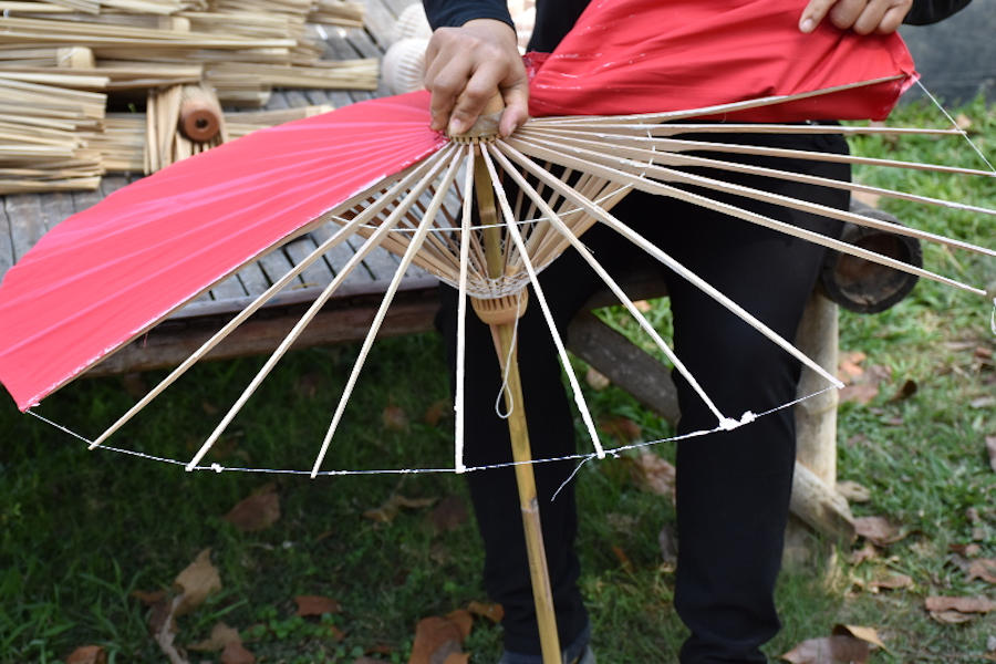 Removing a bamboo umbrella's fabric canopy for replacement.